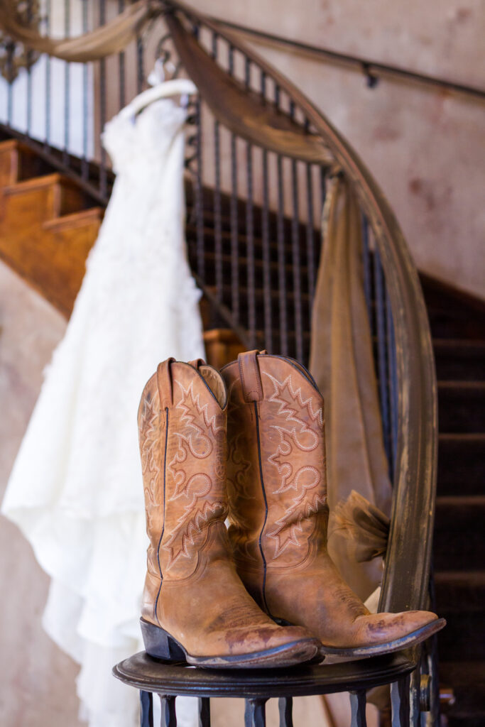 Vintage wedding dress on a hanger with cowboy boots.